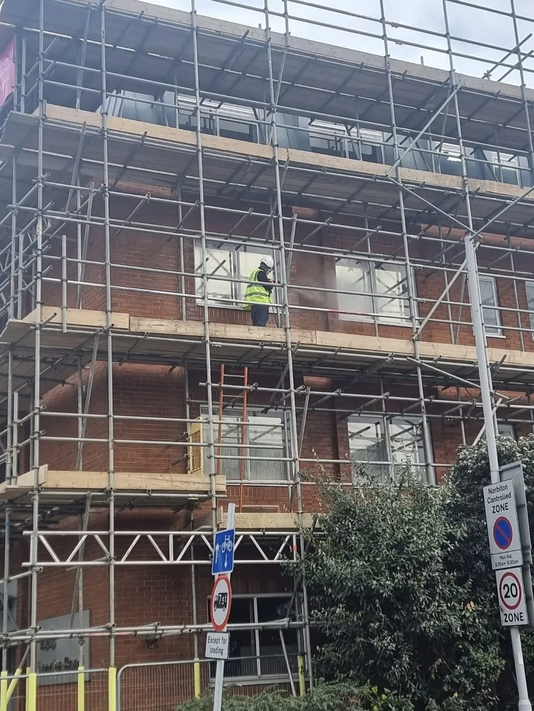 A man standing on a scaffolding in front of a building.