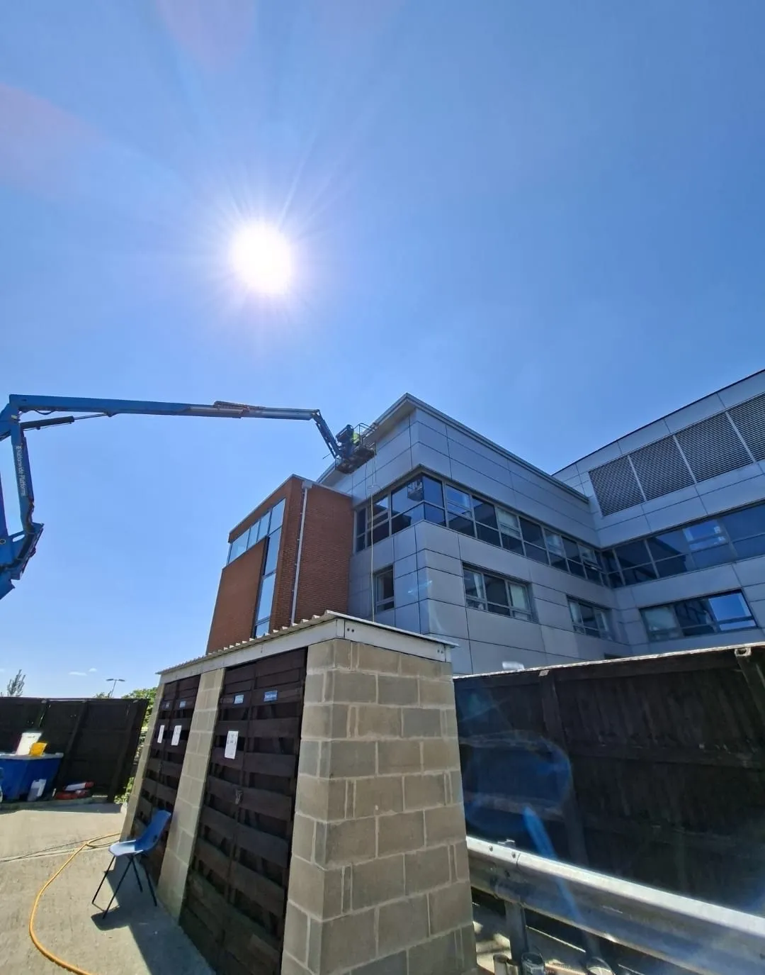 A crane is working on a building in the sun.